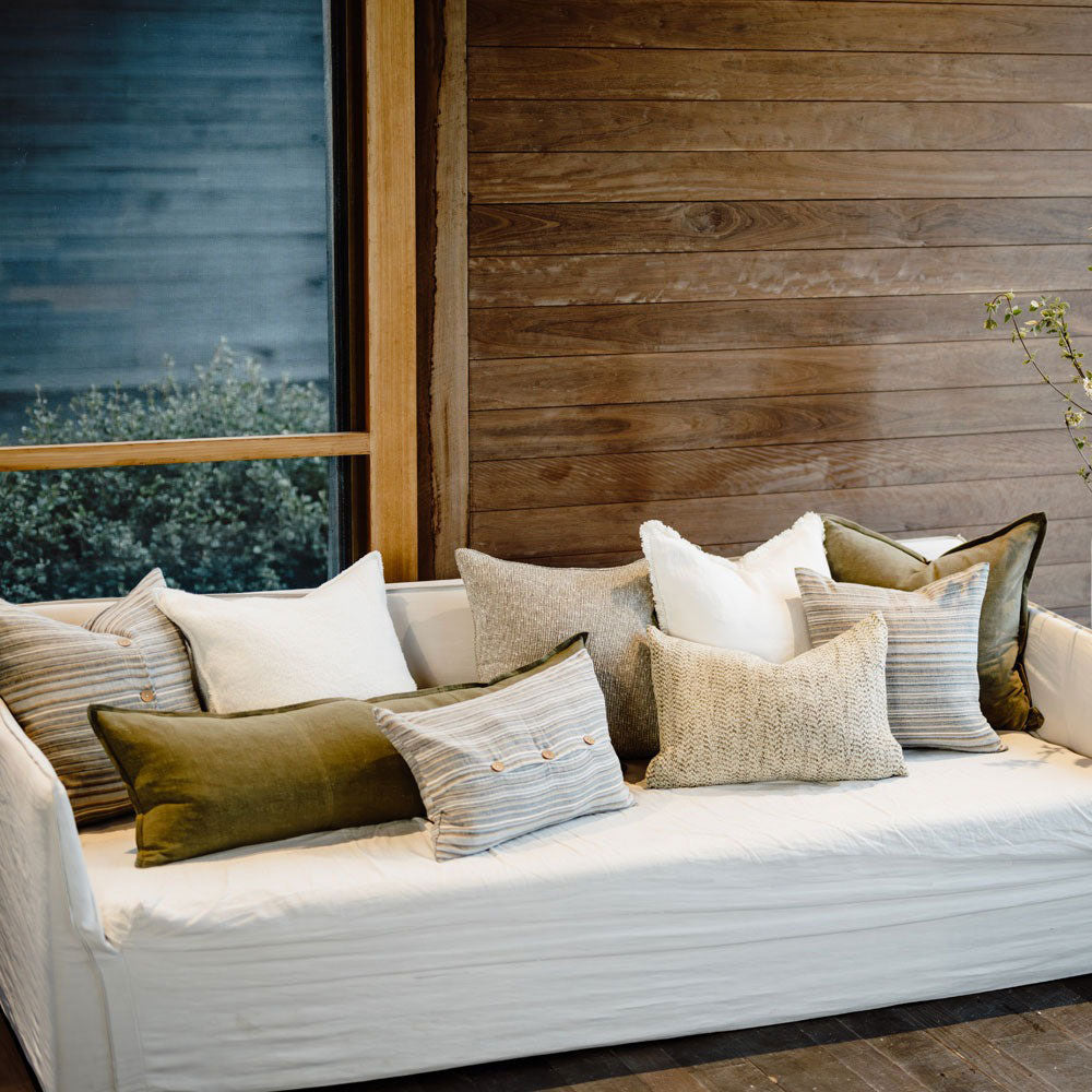 A stylish couch with cushions by Eadie in shades of green, grey, and white, including the Coast striped cushion.