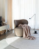 The Baya 'Cromwell Blush' throw blanket draped on a chair in a contemporary living room