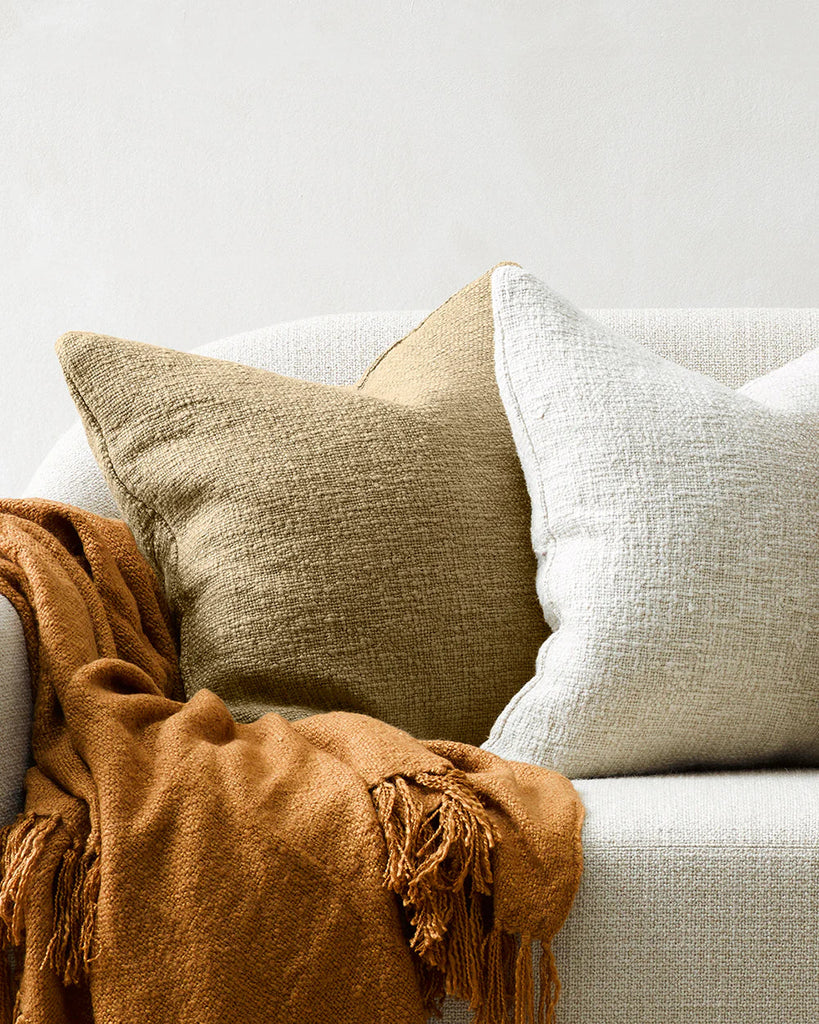 Two Baya cyprian cushions on a couch, with light catching the beautiful slubby texture