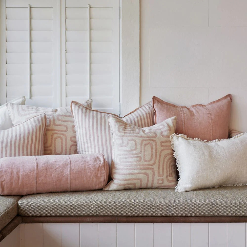 Eadie Lifestyle Drift cushion in White/Soft Musk styled on a window seat with linen cushions in soft pink tones
