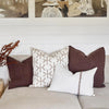 Eadie Lifestyle Luca linen cushions in Chocolate layered with patterned and white cushions.