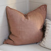 Eadie Lifestyle Luca linen cushion in Clay on a bench seat beside a fringed striped cushion.