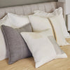 Eadie Lifestyle Luca linen cushion in Grey layered on a bed with white linen cushions.