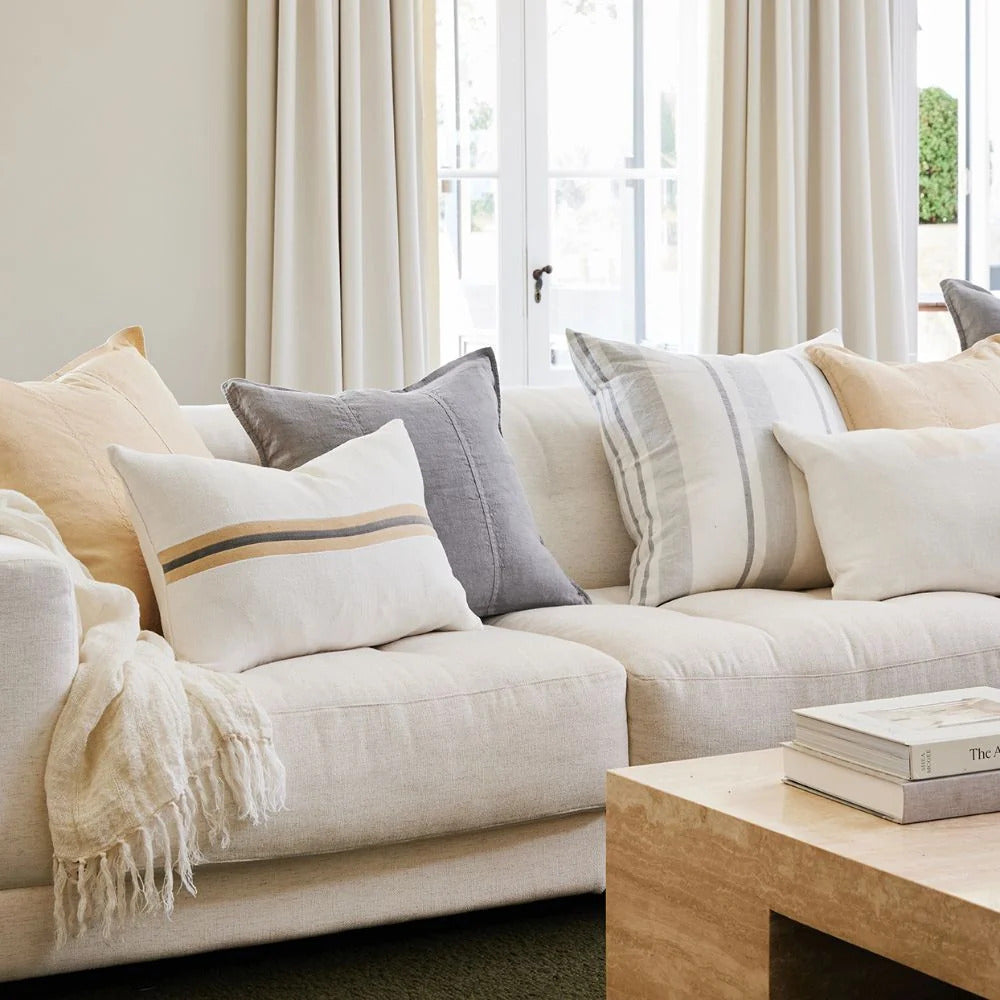 Eadie Lifestyle Luca linen cushion in Grey on a pale linen sofa among neutral cushions.