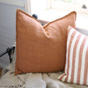 Eadie Lifestyle Luca linen cushion in Nutmeg on a window seat beside a striped cushion.