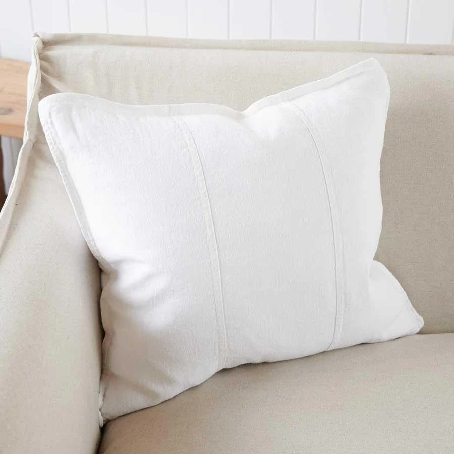 Eadie Lifestyle Luca linen cushion in Off White on a cream sofa against white panelling.