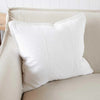 Eadie Lifestyle Luca linen cushion in Off White on a cream sofa against white panelling.