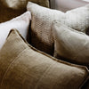 Eadie Lifestyle Luca linen cushion in Olive layered with textured neutral cushions.