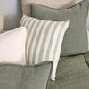 Luca linen cushions in Pistachio layered on a bed with striped and white cushions.