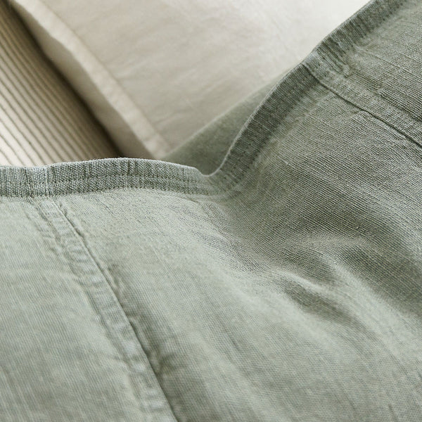 Close view of the washed linen weave and flange edge on the Luca cushion in Pistachio.