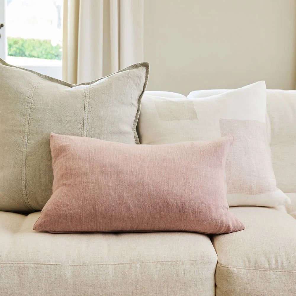 Eadie Lifestyle Luca linen cushion in Putty behind a blush lumbar cushion on a linen sofa.
