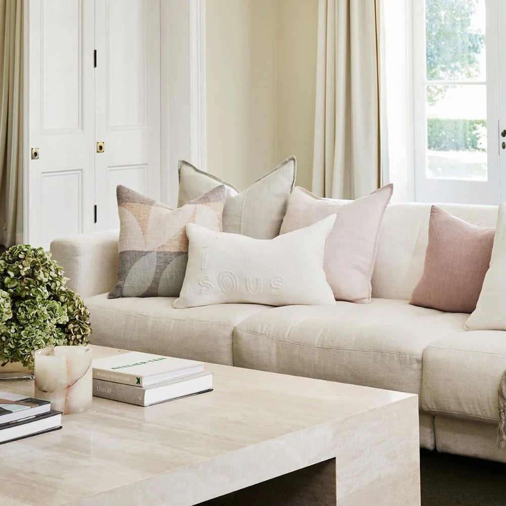 Eadie Lifestyle Luca linen cushion in Putty on a pale linen sofa with blush and neutral cushions.