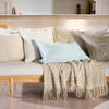Eadie Lifestyle Luca linen cushion in Sky in the lumbar size on a sofa with a fringed throw.