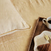 Eadie Lifestyle Luca linen cushion in Soft Butter on a bed with a breakfast tray.