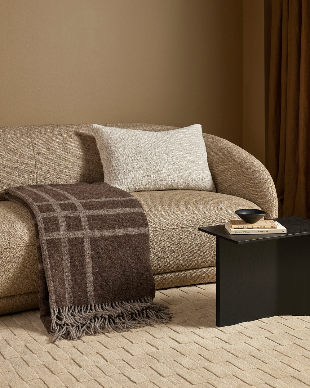 Beige sofa with a brown plaid wool throw blanket in a living room setting.