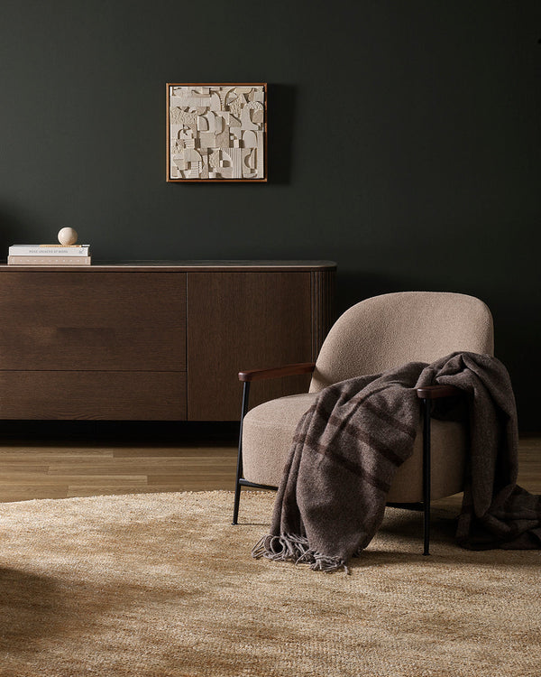 Modern interior with a chair draped with a brown wool throw blanket, a cabinet, and a rug