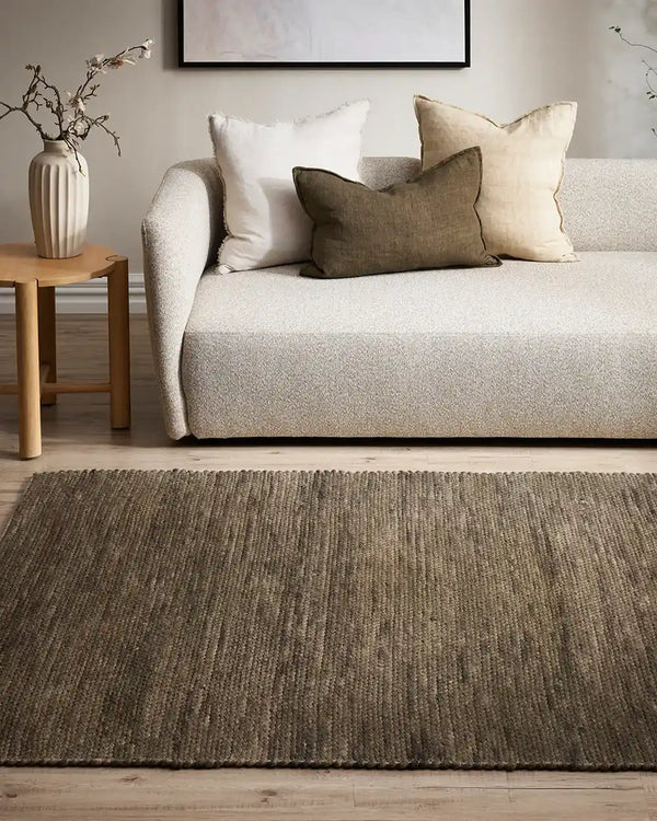 Baya khaki green wool floor rug under a chair and table in a stylish nz living room