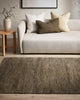 Baya khaki green wool floor rug under a chair and table in a stylish nz living room