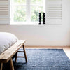 A chic minimalist bedroom in black and white with a deep graphite textured floor rug made with natural jute fibres in a boucle style. 