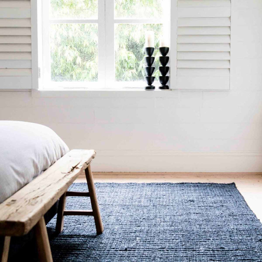 A chic minimalist bedroom in black and white with a deep graphite textured floor rug made with natural jute fibres in a boucle style. 
