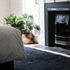 A bohemian style bedroom with a black floor rug made with organic jute fibres. 