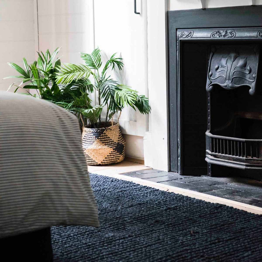 A bohemian style bedroom with a black floor rug made with organic jute fibres. 