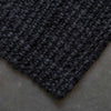 A corner view of a textured black jute floor rug. 