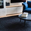 A sitting area with a black boucle woven jute floor rug. 