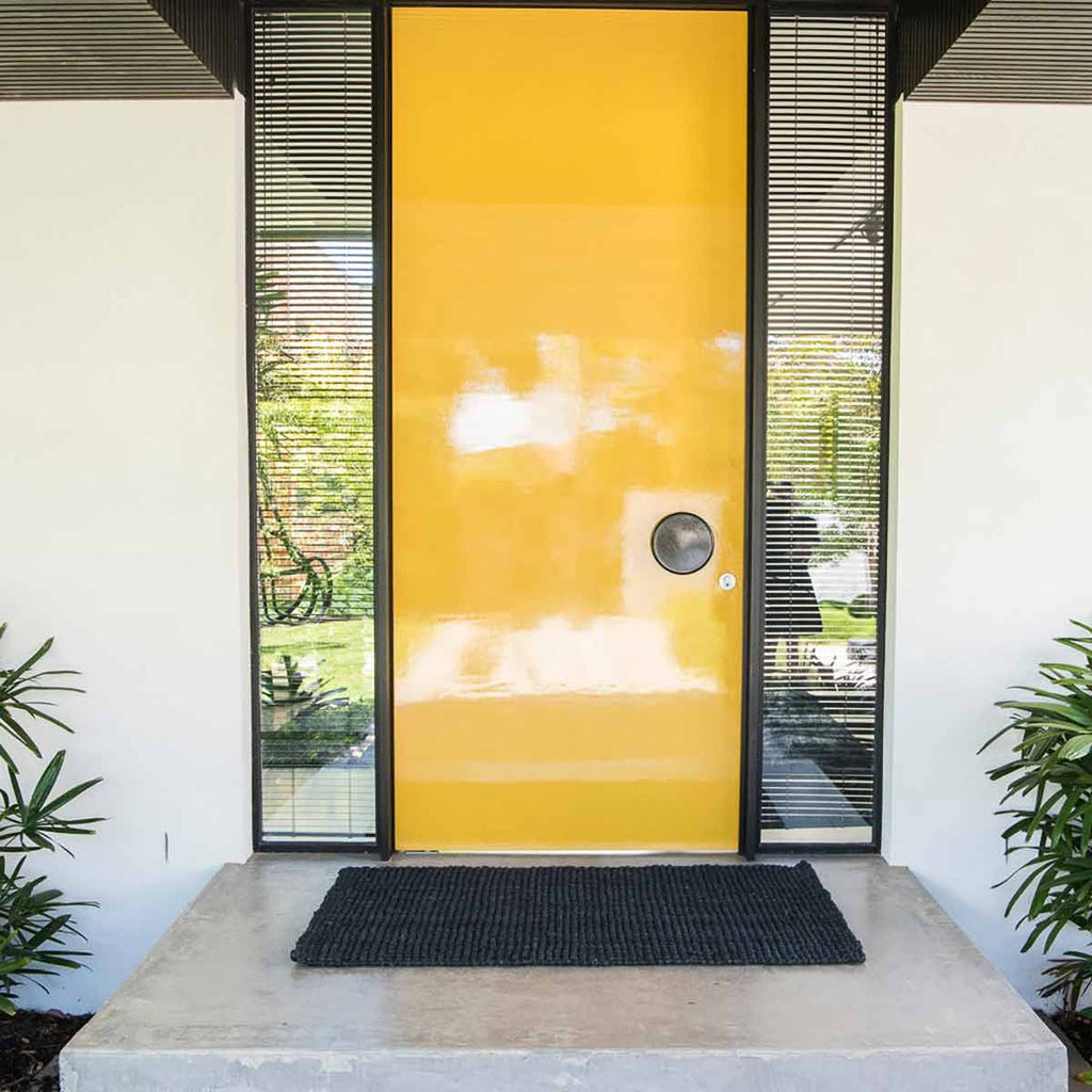A door with a black entrance mat in natural jute fibres. 