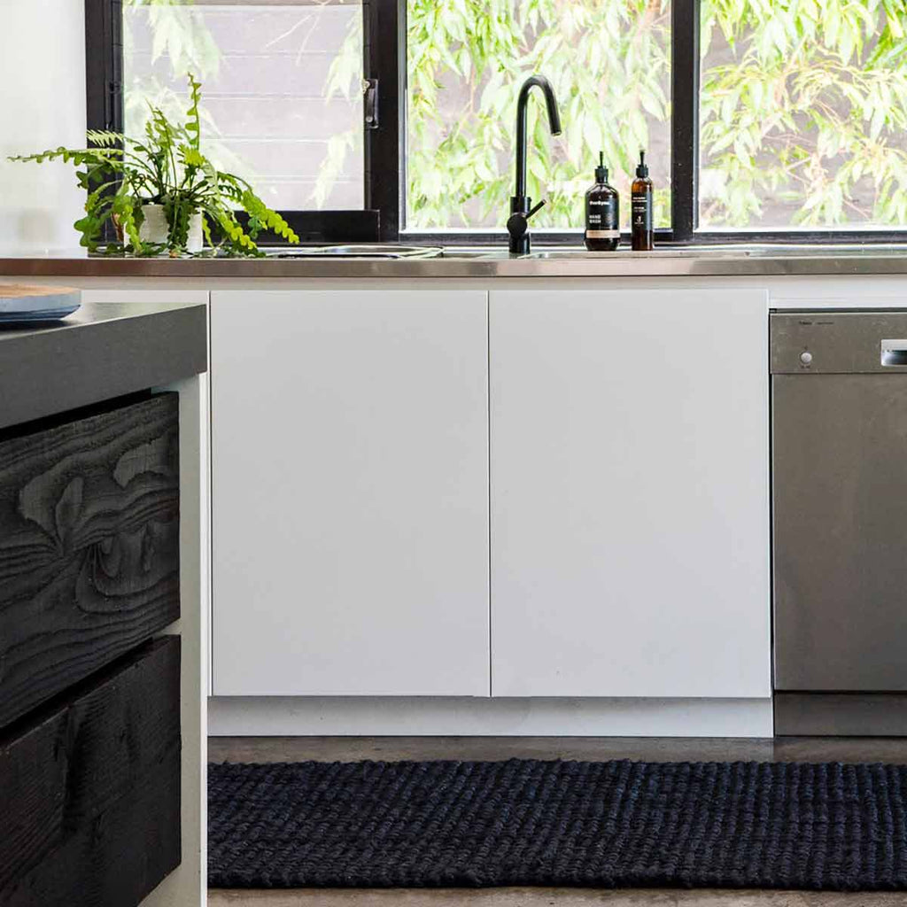 A modern kitchen with a black jute floor runner made with a textured boucle style weave. 
