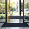 A doorway with an oversized black jute doormat and a floor runner in the same collection. 