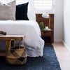 A cozy bedroom with a black floor rug made in a textured boucle style with natural jute fibres. 