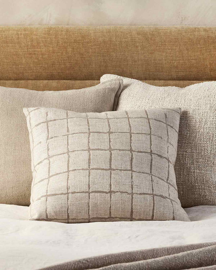 Baya designer cushions in natural linen-look and taupe, inspired by Japanese design, seen together on a  modern bed