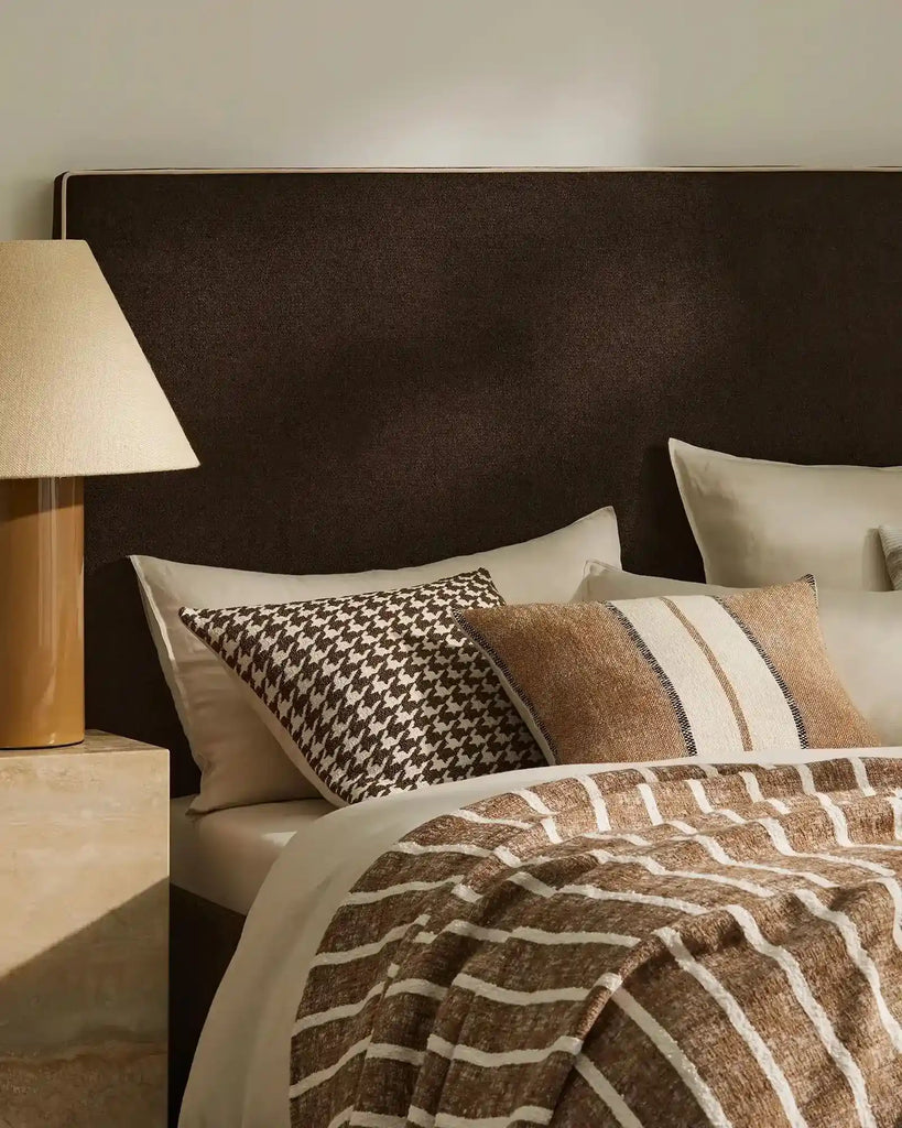 Brown , black and cream patterned cushions by Weave Home nz, on a bed in a stylish bedroom