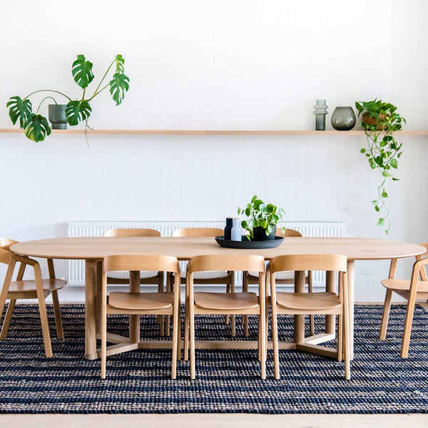 A minimalist dining room with a blue/black floor rug made with durable jute fibres, with brown striping. 