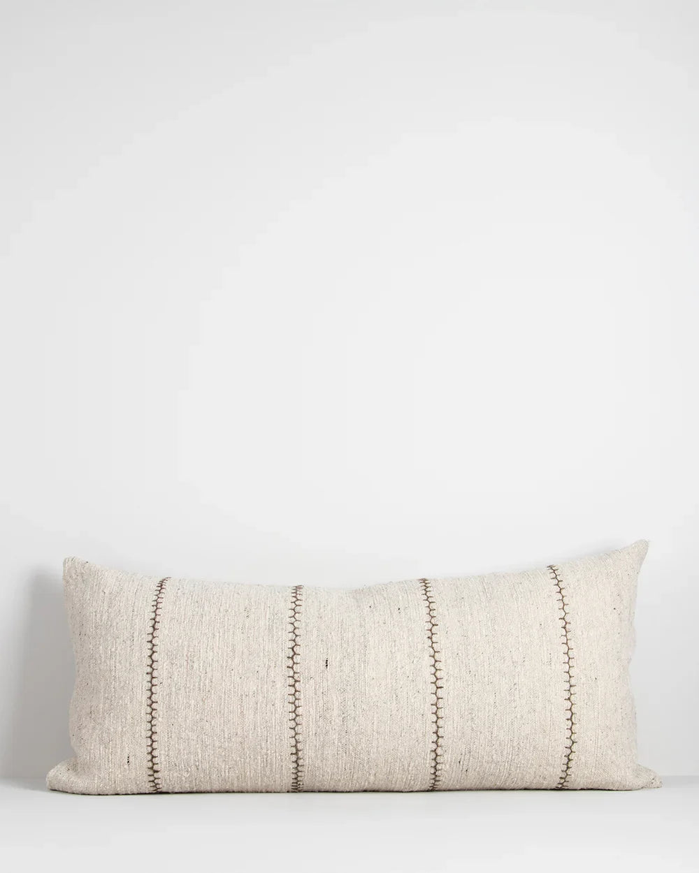 An extra-long lumbar, textural cotton cushion featuring a delicate Cretan-stitch is embroidered in khaki over a natural, ecru-toned base.