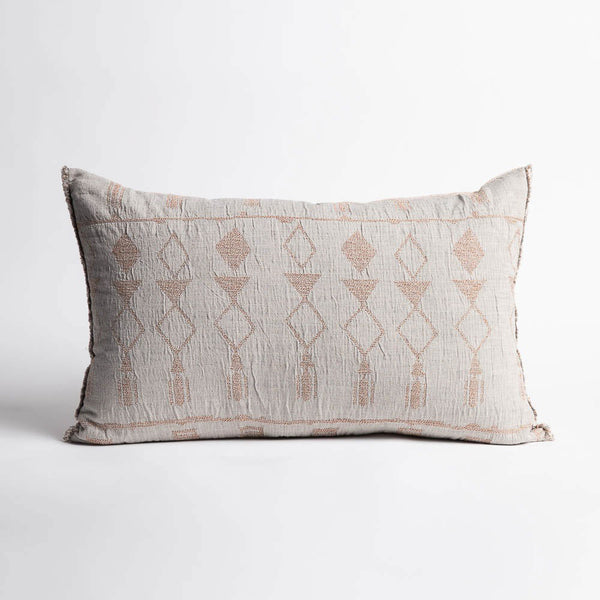 A patterned cushion in lumbar shape, with pale blue and soft clay tones in a geometric pattern, reversed, and a softly fringed edge.