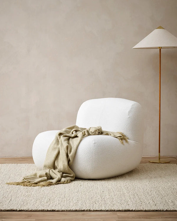 The Baya 'Richmond Putty' throw blanket, draped over a chair in a modern living room