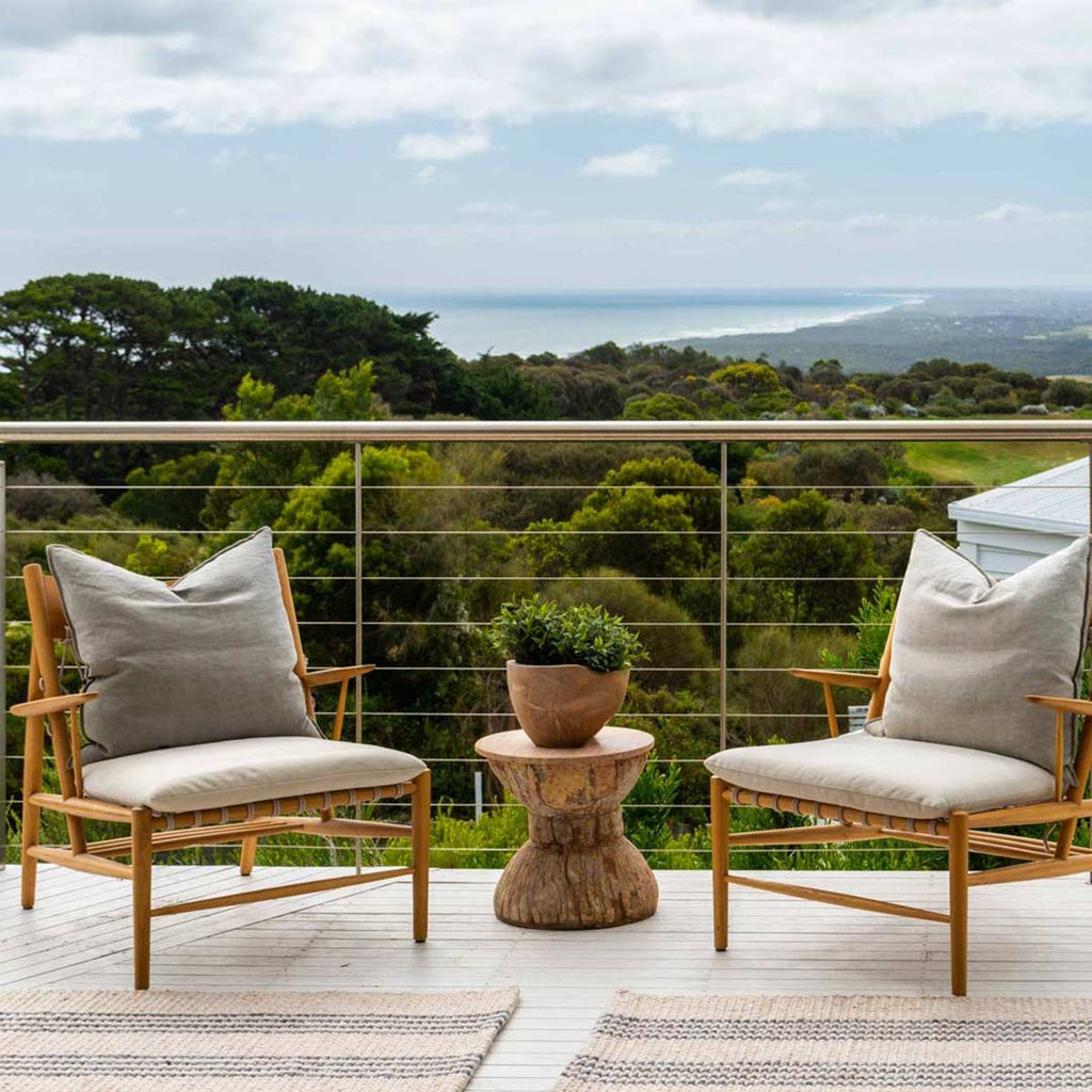 A deck with a beautiful ocean view, and two natural beige mats made with 100% recycled PET and with slate grey stripes. 