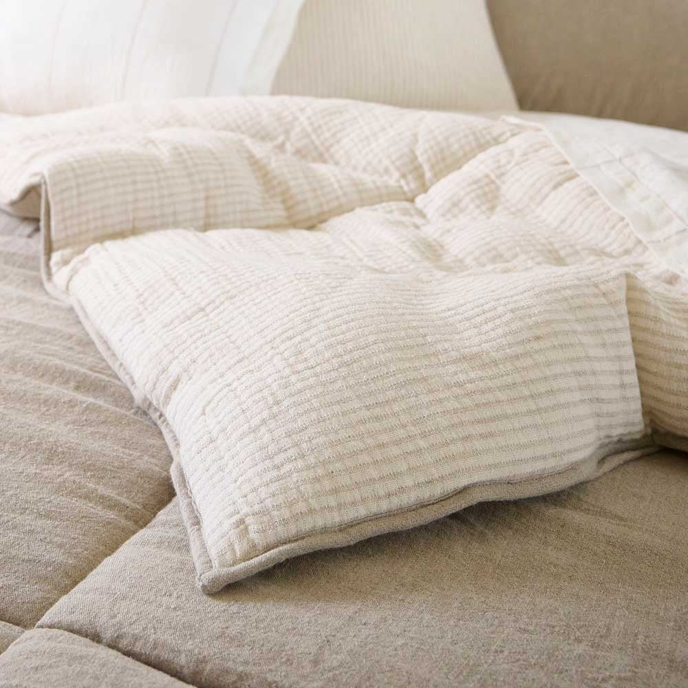 A turned over corner of the Marina quilted bedspread, the underneath a gorgeous cream with taupe stripes and the outer side a cool beige block pattern. 