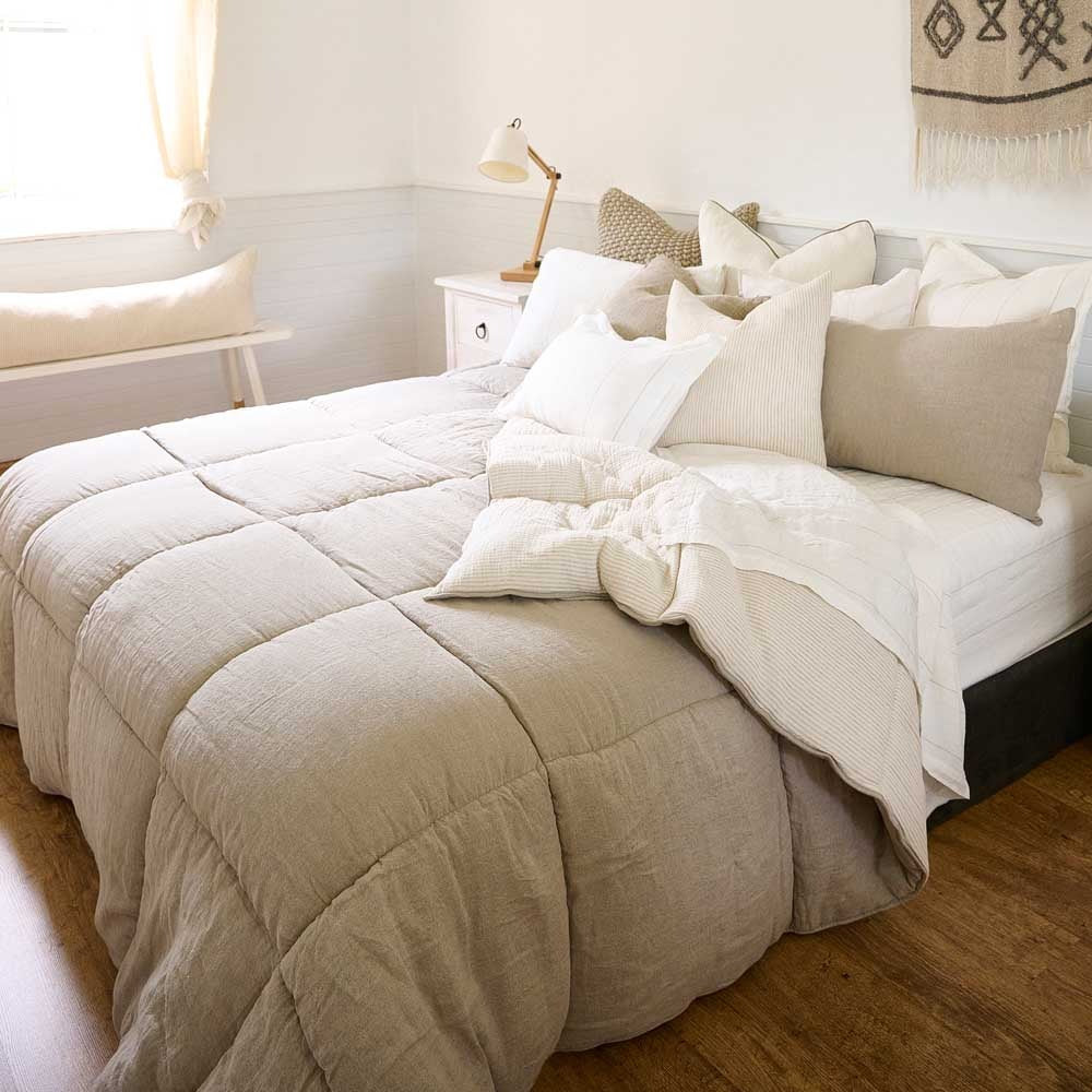 A cozy looking bed with a taupe quilted block patterned bed cover, by Eadie Lifestyle 