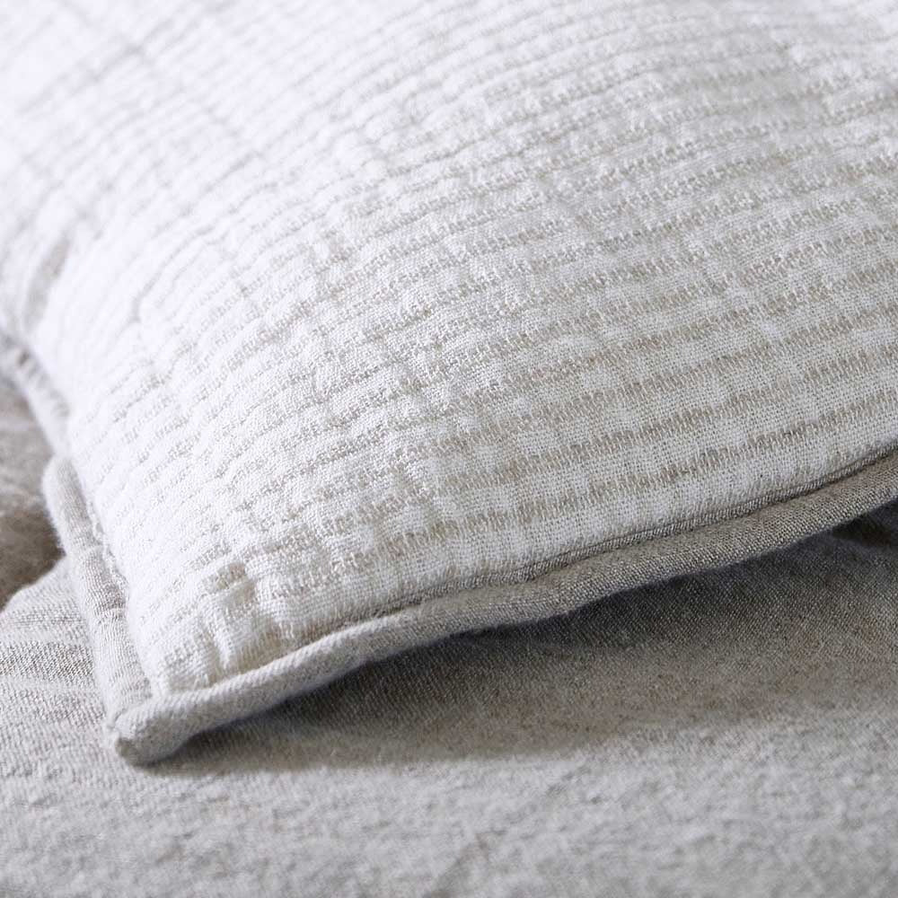 A close up image of the gorgeous cotton blend Marina bedcover, with beige and taupe neutral stripes and a reversible pattern. 