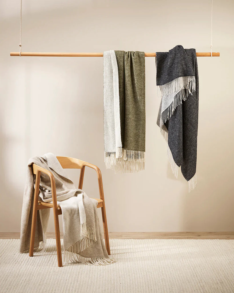 A collection of neutral merino throws draped in various ways 