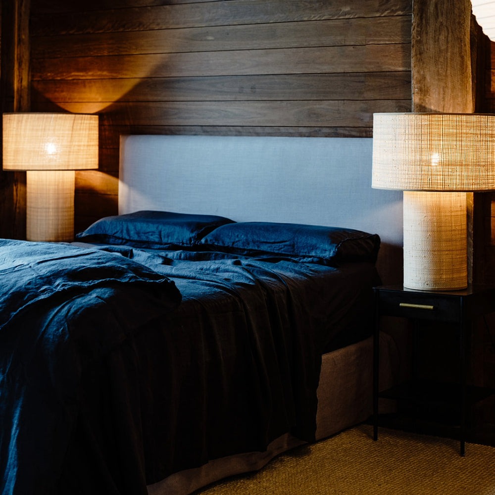 A sophisticated bedroom, with a bed with midnight blue sheets, duvet cover, and pillows in soft French flax linen, by Eadie Lifestyle. 