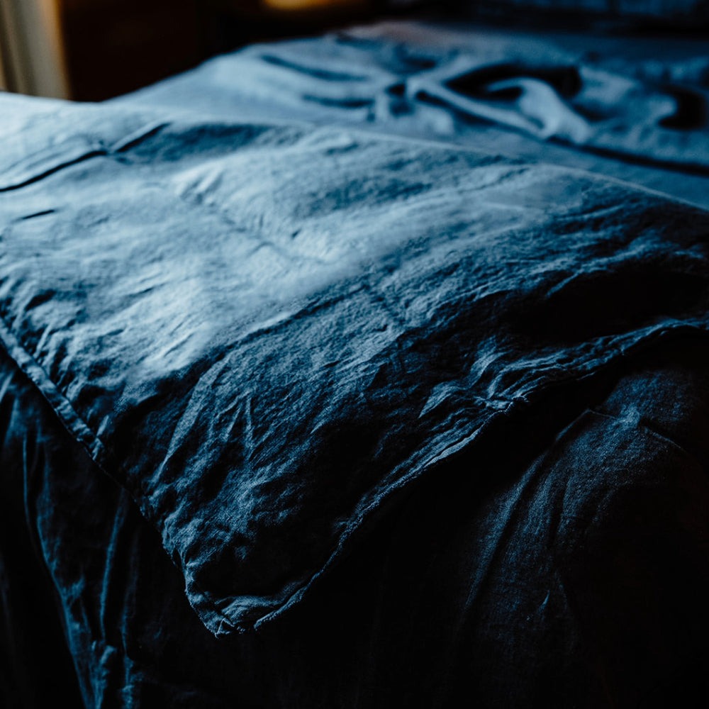 A corner image of Eadie Lifestyle's French flax linen duvet cover, in beautiful midnight blue. 