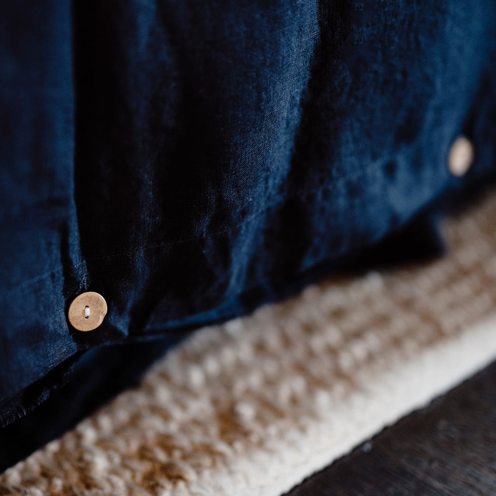 A close up of the button closures of the Eadie duvet cover in French Flax Linen, shade Midnight blue. 