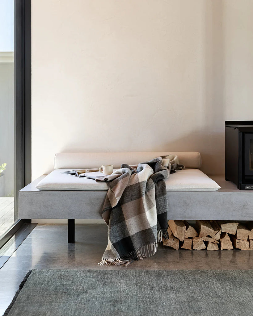 Nz made wool throw blanket in a modern plaid featuring blush browns, black and cream, in a modern home