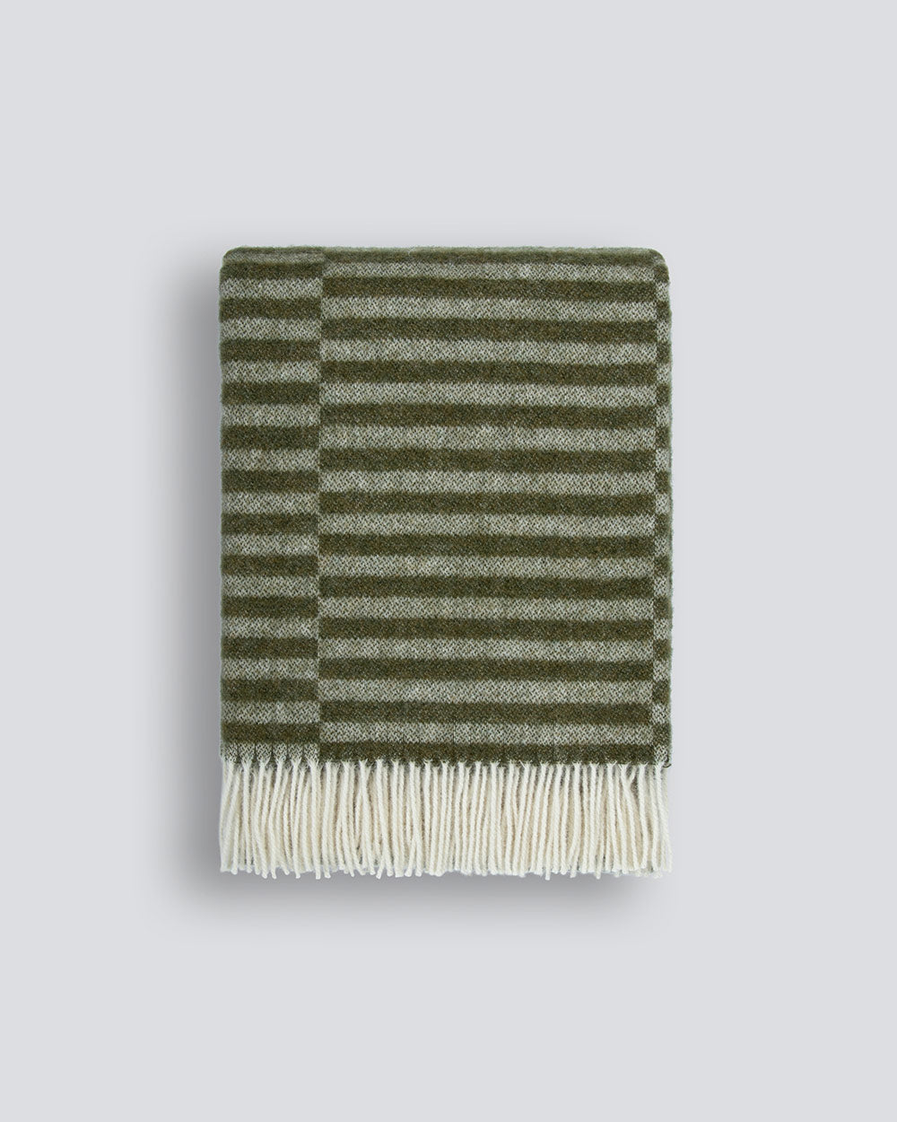 An off-set striped patterned throw blanket in shades of soft sage-green and olive, with a twisted fringe edge in 100% NZ wool by Baya