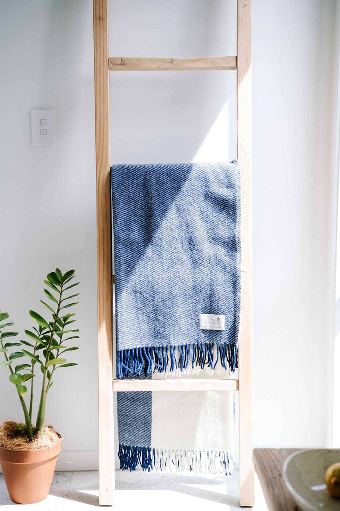 NZ wool throw blanket in blue nad white stripe, by Ruanui Station, seen hanging