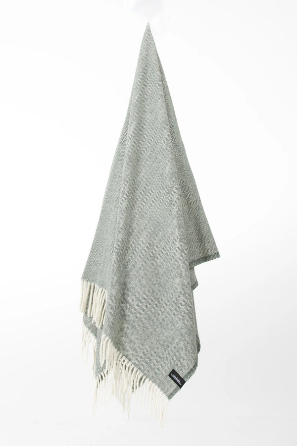 Palliser Ridge Herringbone throw in Forest hanging in full drape, showing the fringed edge